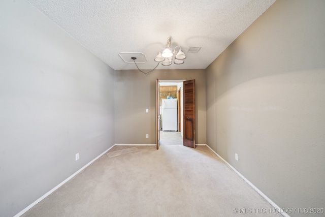 spare room featuring visible vents, light colored carpet, a textured ceiling, and baseboards