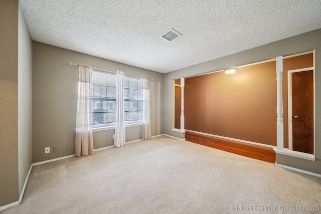 spare room featuring visible vents, baseboards, carpet, and a textured ceiling