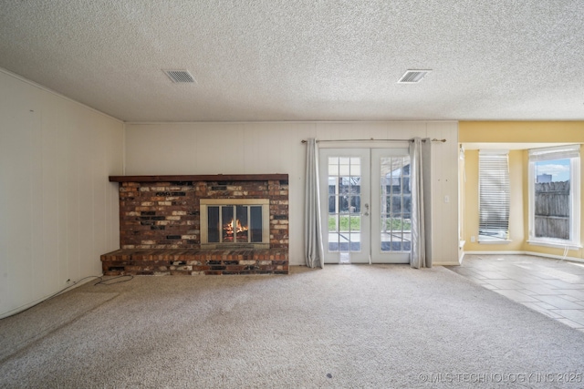 unfurnished living room featuring visible vents, carpet, a fireplace, and french doors