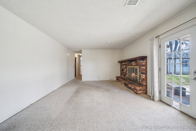 unfurnished living room with visible vents, a brick fireplace, a textured ceiling, and carpet