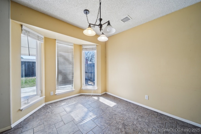 unfurnished room featuring baseboards, visible vents, a textured ceiling, and an inviting chandelier