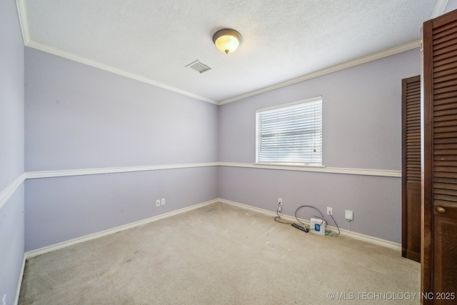 unfurnished room with visible vents, a textured ceiling, crown molding, and carpet floors