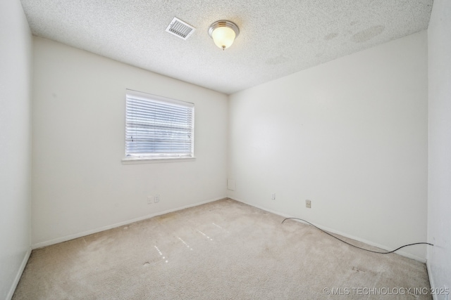 unfurnished room featuring carpet flooring, visible vents, and a textured ceiling