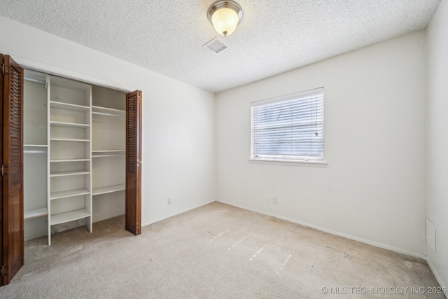 unfurnished bedroom with visible vents, baseboards, carpet floors, a closet, and a textured ceiling