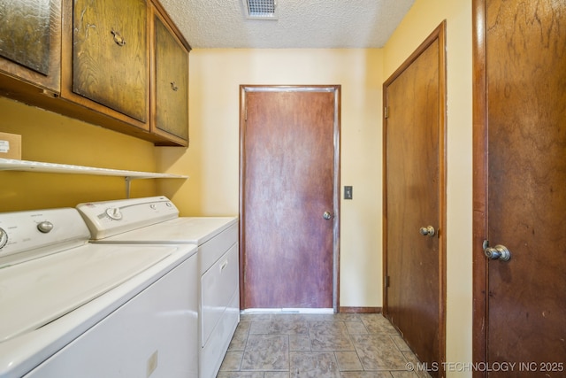 washroom featuring washer and clothes dryer, visible vents, cabinet space, and a textured ceiling