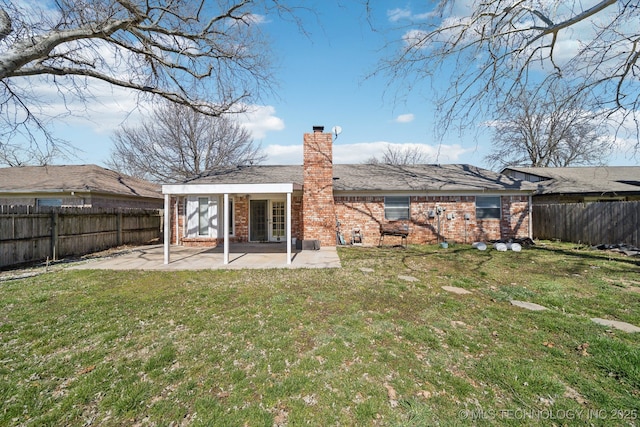 back of property featuring brick siding, a lawn, a chimney, a fenced backyard, and a patio area