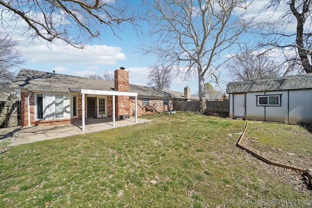 view of yard featuring a patio, a storage unit, a fenced backyard, and an outbuilding