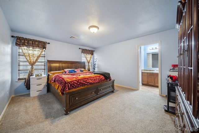 bedroom featuring light carpet, visible vents, ensuite bath, and baseboards