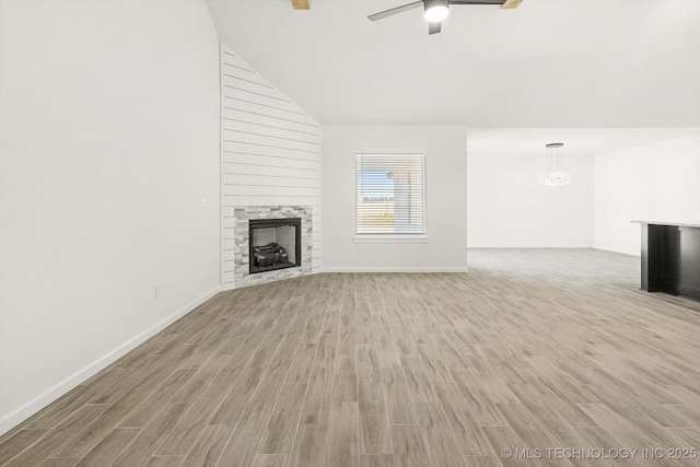 unfurnished living room with a ceiling fan, baseboards, a fireplace, vaulted ceiling, and light wood-style floors