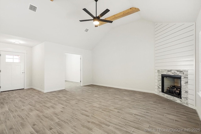 unfurnished living room with visible vents, a large fireplace, a ceiling fan, and wood finished floors