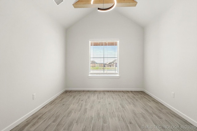 empty room featuring visible vents, baseboards, lofted ceiling, and wood finished floors