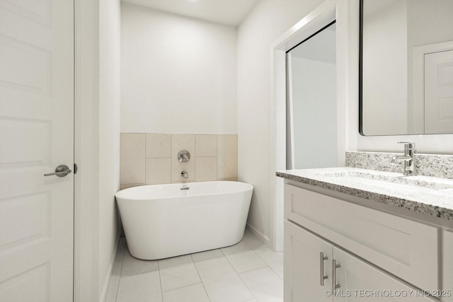 bathroom featuring tile patterned floors, a soaking tub, vanity, and tile walls