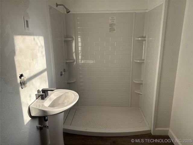 bathroom featuring baseboards, a shower stall, and a textured wall