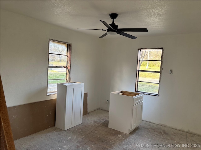 empty room with plenty of natural light, a textured ceiling, and a ceiling fan