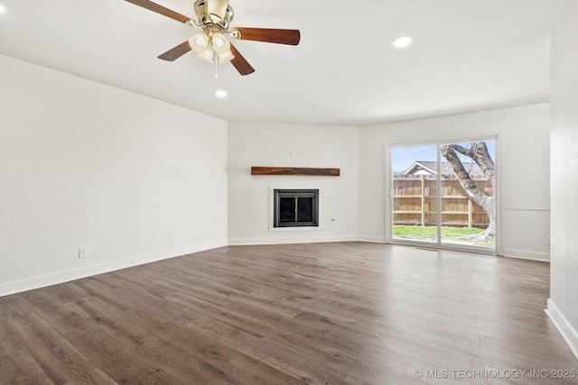 unfurnished living room with a fireplace, wood finished floors, baseboards, and a ceiling fan