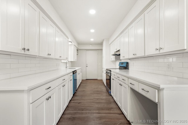 kitchen featuring a sink, under cabinet range hood, appliances with stainless steel finishes, white cabinetry, and dark wood-style flooring