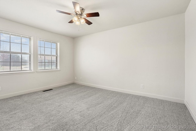 unfurnished room featuring carpet flooring, a ceiling fan, visible vents, and baseboards