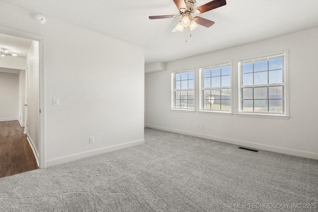 carpeted empty room featuring visible vents, baseboards, and ceiling fan