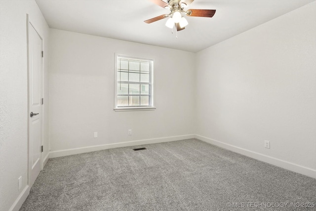 carpeted spare room featuring baseboards, visible vents, and ceiling fan