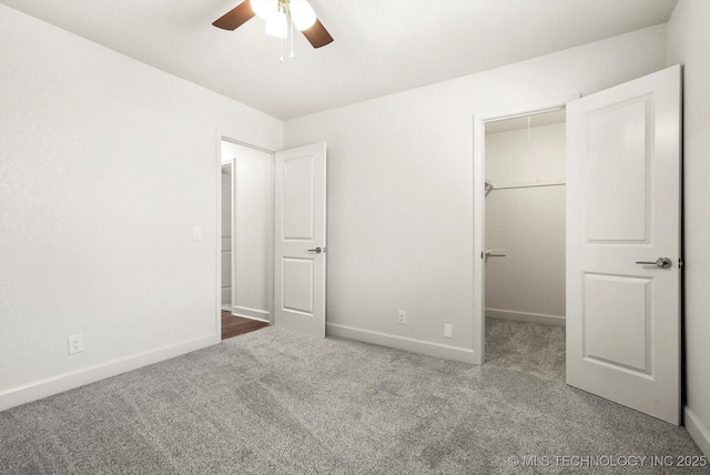 unfurnished bedroom featuring baseboards, carpet floors, ceiling fan, a closet, and a walk in closet