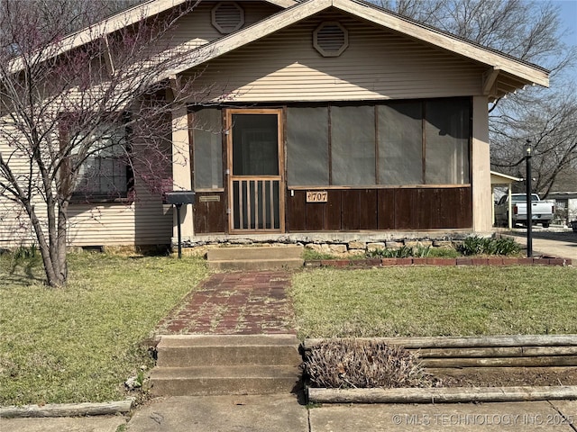 view of front facade with a front yard and a sunroom