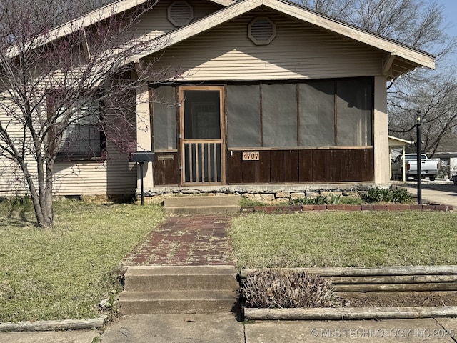 view of front of property with a front yard and a sunroom