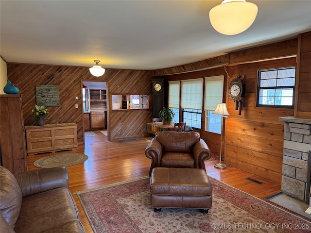 living area with visible vents, wooden walls, and wood finished floors