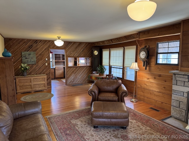 living room featuring visible vents, wood walls, and wood finished floors