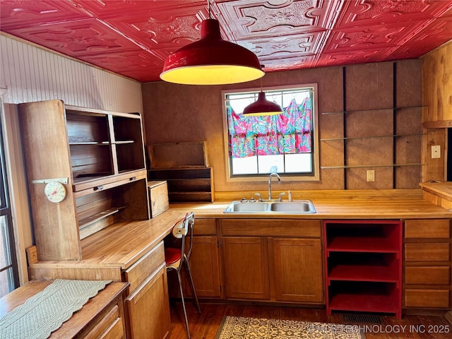 kitchen featuring wood finished floors, brown cabinetry, an ornate ceiling, and a sink