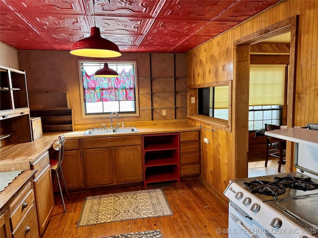 kitchen with light countertops, wood walls, an ornate ceiling, and a sink