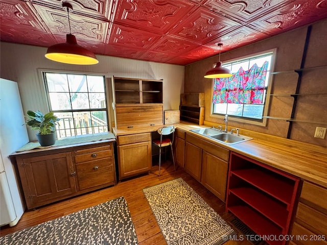 kitchen featuring a sink, pendant lighting, brown cabinetry, an ornate ceiling, and open shelves