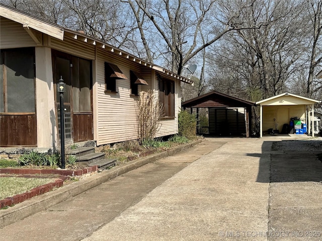 view of home's exterior with a detached carport, driveway, and entry steps