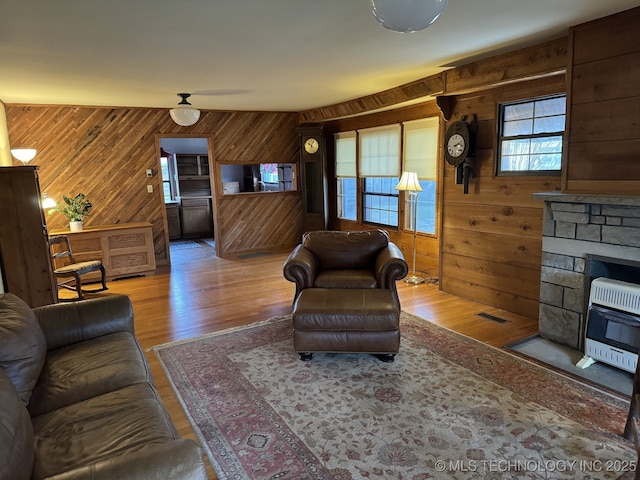 707 E 15th St, Okmulgee, OK 74447 - living area with wooden walls, wood finished floors, heating unit, and a stone fireplace