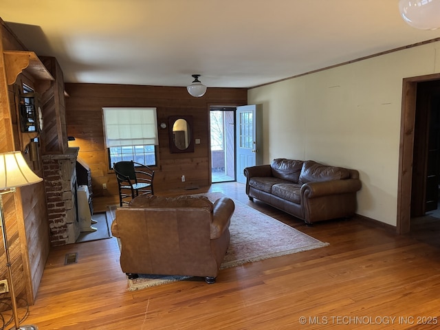 707 E 15th St, Okmulgee, OK 74447 - living area with light wood-type flooring, wooden walls, a brick fireplace, and crown molding