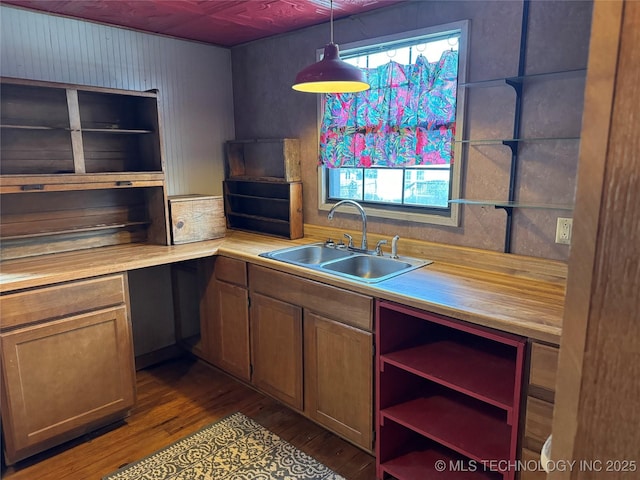 kitchen featuring open shelves, light countertops, dark wood-type flooring, and a sink