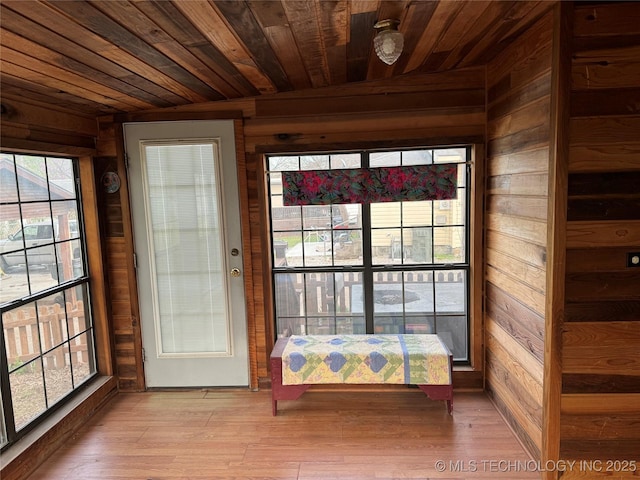 entryway featuring light wood finished floors, wood walls, and wooden ceiling