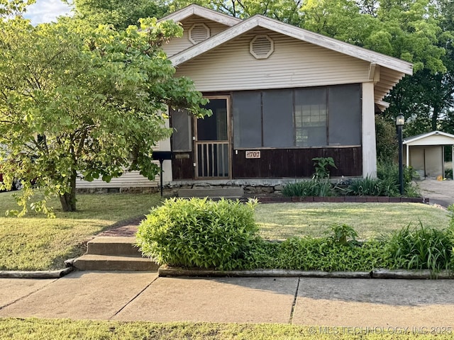 707 E 15th St, Okmulgee, OK 74447 - view of front facade featuring a sunroom, crawl space, a front yard, and a detached carport