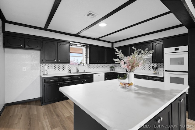 kitchen featuring visible vents, a sink, light countertops, white appliances, and dark cabinets