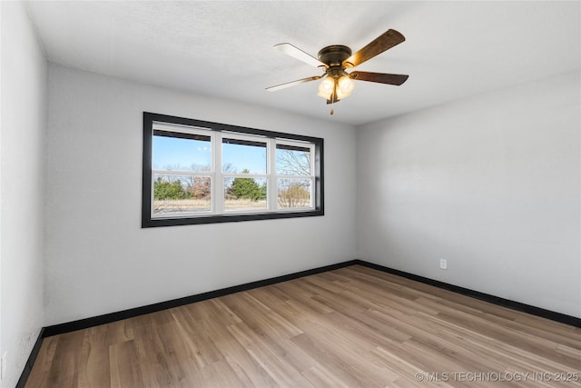 empty room featuring light wood-style flooring, a ceiling fan, and baseboards