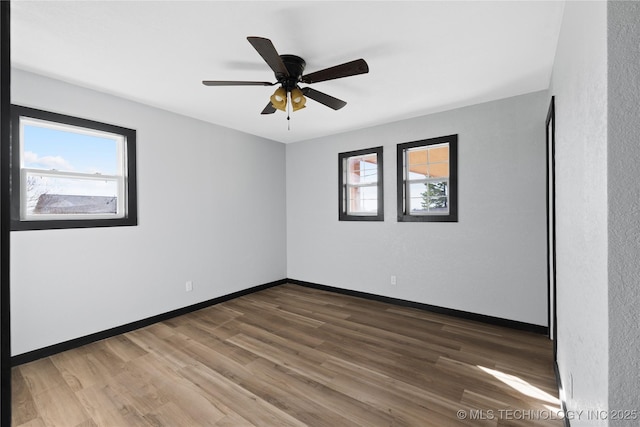 unfurnished room with a ceiling fan, baseboards, and wood finished floors