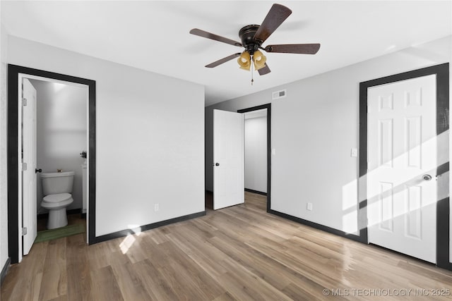 unfurnished bedroom featuring light wood finished floors, visible vents, ceiling fan, baseboards, and ensuite bath