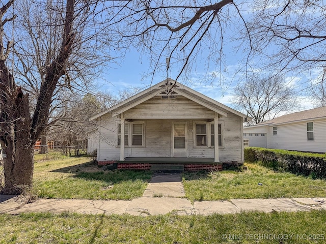 bungalow featuring a porch, fence, and a front yard