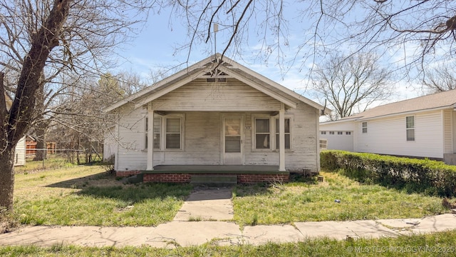 view of front of property featuring a porch, an outdoor structure, and fence