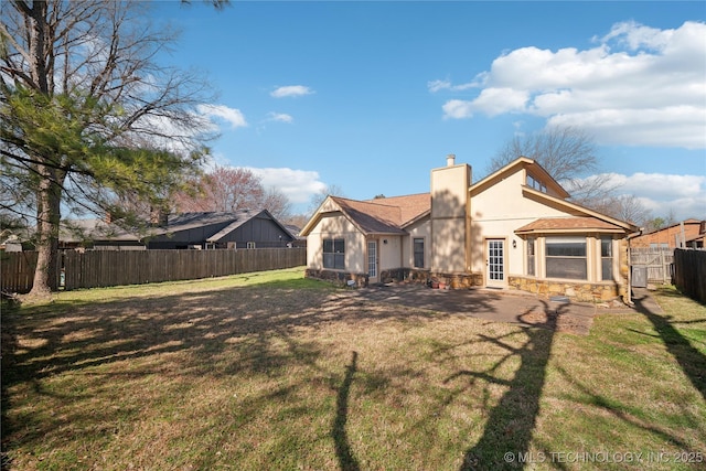 rear view of property featuring stucco siding, a lawn, stone siding, a fenced backyard, and a chimney