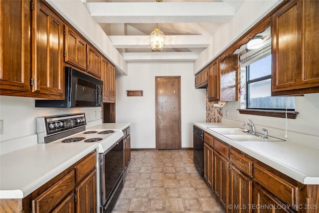 kitchen with black appliances, a sink, brown cabinetry, light countertops, and baseboards