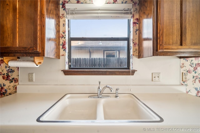 kitchen featuring brown cabinetry, light countertops, and a sink