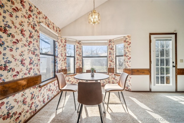 carpeted dining area featuring a notable chandelier, a textured ceiling, and high vaulted ceiling