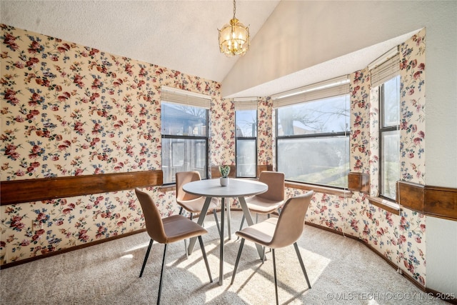 dining room featuring lofted ceiling, an inviting chandelier, carpet flooring, and wallpapered walls