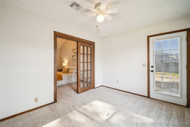 carpeted empty room with baseboards, visible vents, a textured ceiling, and ceiling fan