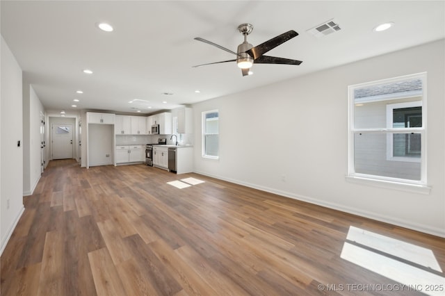 unfurnished living room with recessed lighting, visible vents, baseboards, and wood finished floors